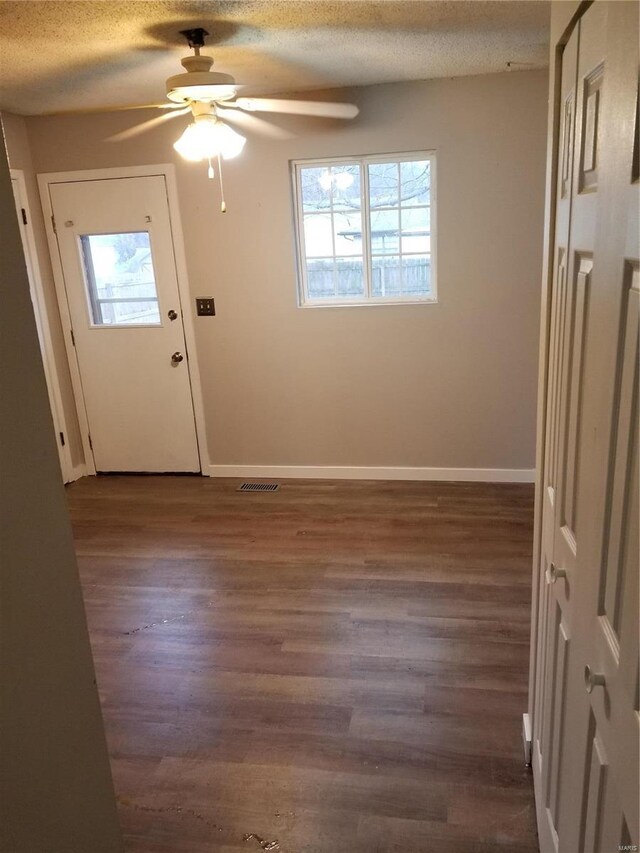 doorway to outside with a textured ceiling, ceiling fan, and dark wood-type flooring