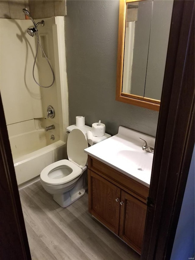 full bathroom with bathing tub / shower combination, vanity, wood-type flooring, and toilet