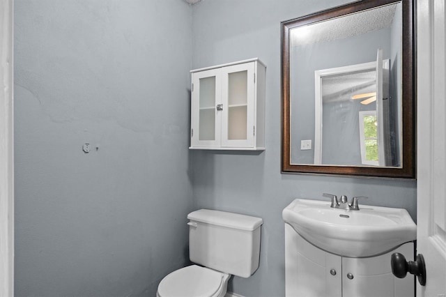bathroom featuring toilet, baseboards, and vanity