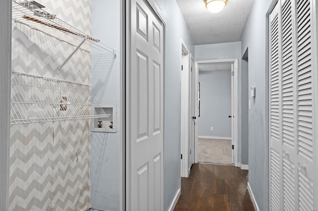 hallway with baseboards, a textured ceiling, and wood finished floors