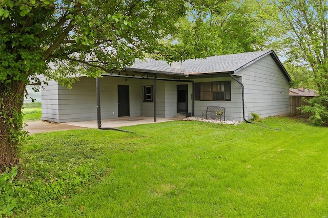 view of front of property with fence, a shingled roof, a patio area, and a front lawn