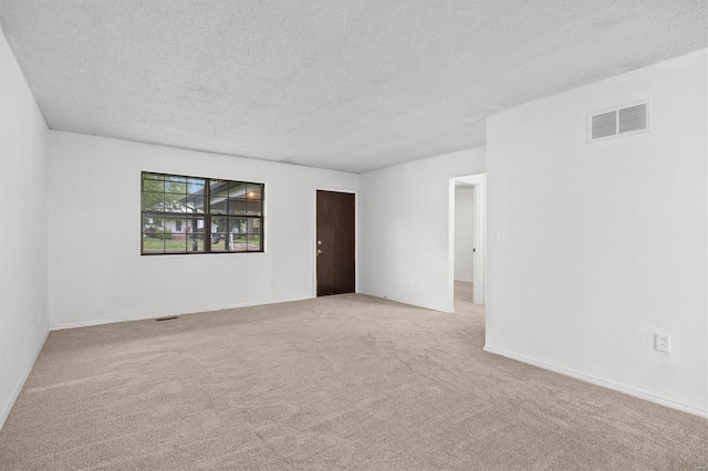 spare room with a textured ceiling, visible vents, and carpet