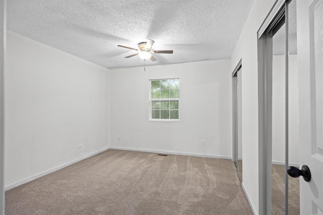 unfurnished bedroom featuring baseboards, a textured ceiling, carpet, and ceiling fan