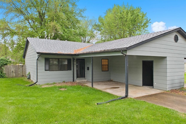 ranch-style home featuring fence, roof with shingles, and a front lawn