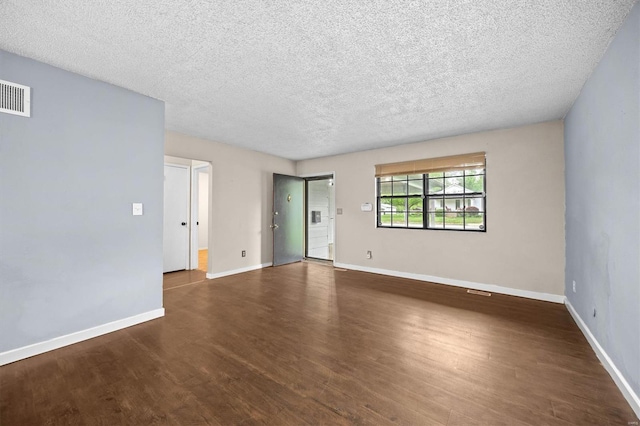spare room featuring baseboards, a textured ceiling, visible vents, and wood finished floors