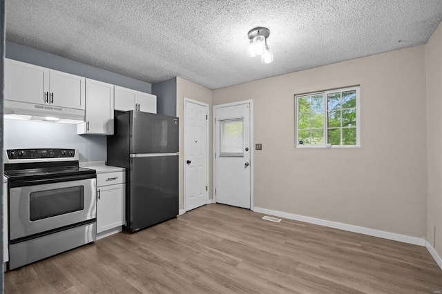 kitchen featuring visible vents, light wood-type flooring, stainless steel range with electric stovetop, freestanding refrigerator, and under cabinet range hood