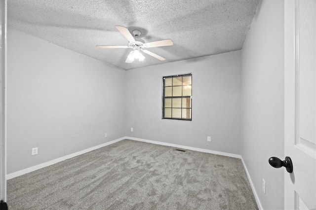 carpeted spare room with baseboards, a ceiling fan, and a textured ceiling