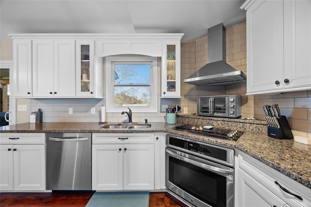 kitchen featuring wall chimney exhaust hood, appliances with stainless steel finishes, tasteful backsplash, and a sink