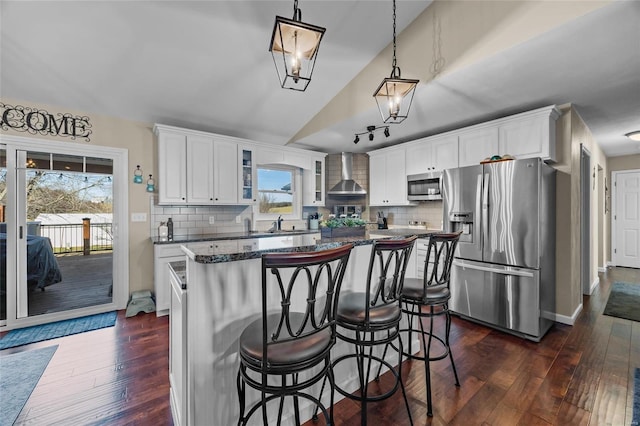 kitchen with stainless steel appliances, wall chimney range hood, a center island, dark wood-style floors, and glass insert cabinets