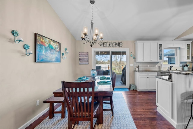 dining space featuring vaulted ceiling, an inviting chandelier, dark wood-style floors, and baseboards