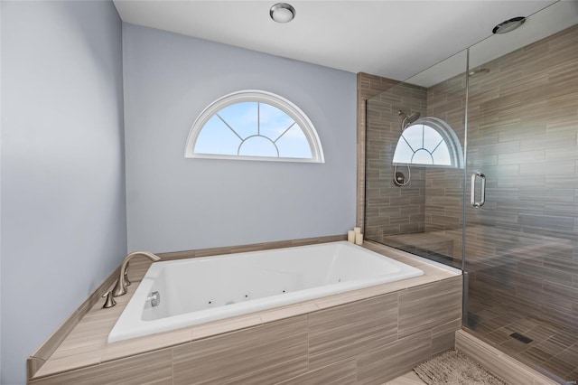 full bathroom featuring a whirlpool tub, a shower stall, and a wealth of natural light