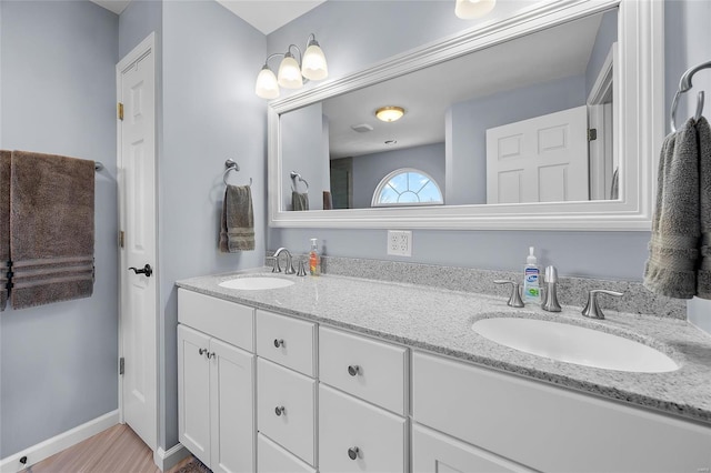 bathroom featuring double vanity, baseboards, and a sink