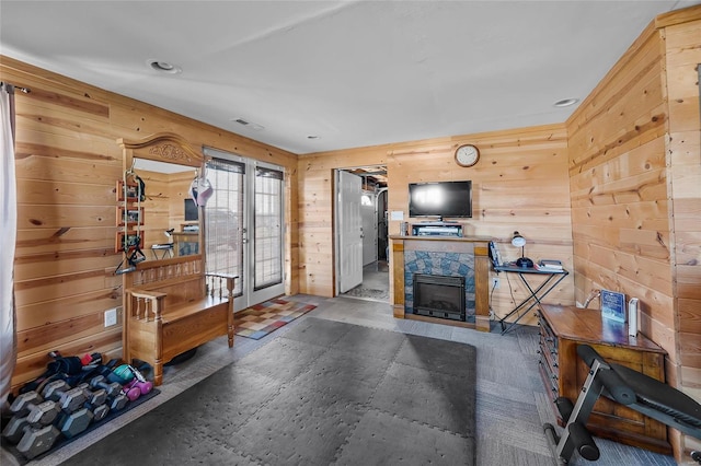 interior space featuring wood walls, visible vents, french doors, and a stone fireplace