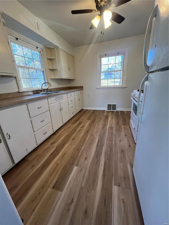 kitchen with white cabinets, white appliances, light hardwood / wood-style flooring, and sink