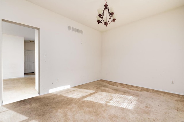 carpeted spare room featuring a notable chandelier