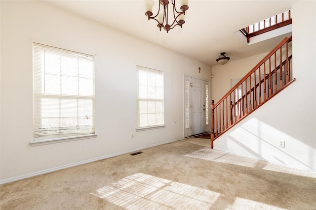 carpeted entrance foyer featuring a wealth of natural light and a chandelier