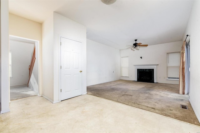 unfurnished living room featuring a premium fireplace, ceiling fan, and light colored carpet