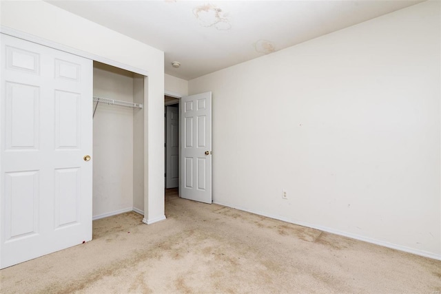 unfurnished bedroom with light colored carpet and a closet