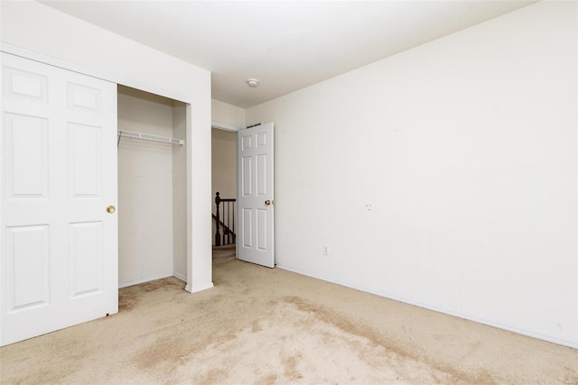 unfurnished bedroom featuring light carpet and a closet