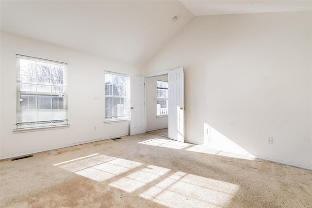 carpeted empty room with high vaulted ceiling and plenty of natural light