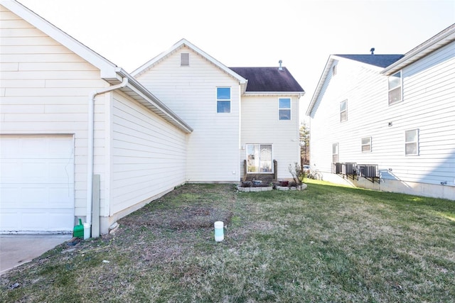 rear view of property with a garage, a lawn, and central air condition unit