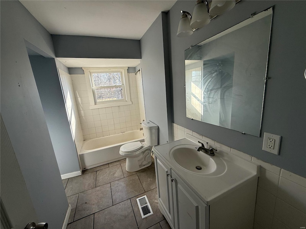 full bathroom with tile patterned floors, vanity, tiled shower / bath, and toilet