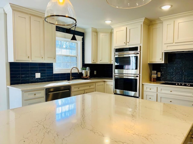 kitchen with sink, hanging light fixtures, light stone counters, decorative backsplash, and appliances with stainless steel finishes