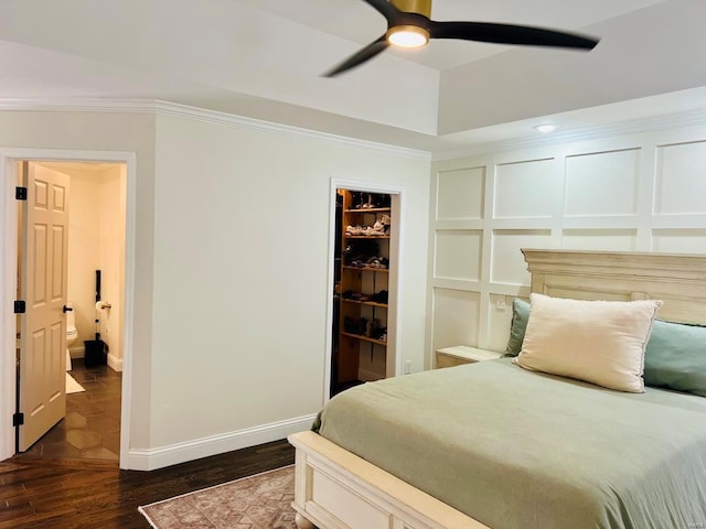 bedroom featuring ceiling fan, dark hardwood / wood-style floors, a walk in closet, a closet, and ornamental molding