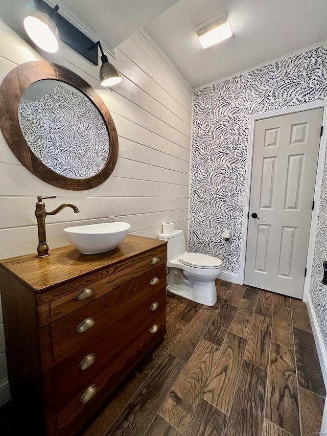 bathroom with ornamental molding, vanity, wood-type flooring, and toilet