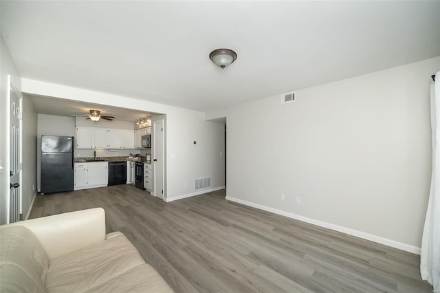 living room featuring ceiling fan, light hardwood / wood-style floors, and sink