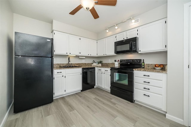 kitchen featuring light hardwood / wood-style flooring, dark stone counters, black appliances, and white cabinetry