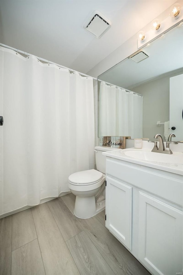 bathroom featuring toilet, hardwood / wood-style floors, and vanity