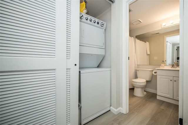 laundry room with light hardwood / wood-style flooring and stacked washer and dryer