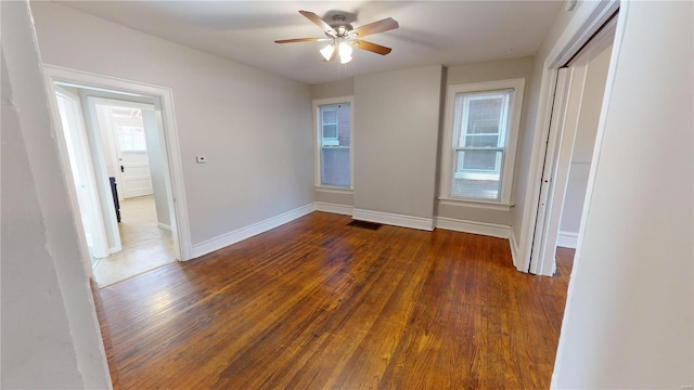 empty room featuring ceiling fan, dark hardwood / wood-style flooring, and a healthy amount of sunlight