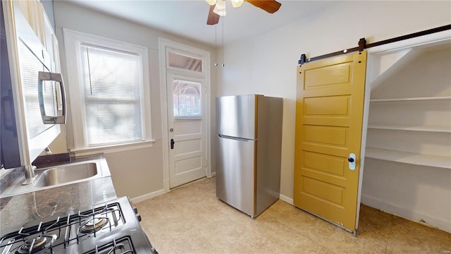 kitchen with range, a barn door, stainless steel refrigerator, and a wealth of natural light