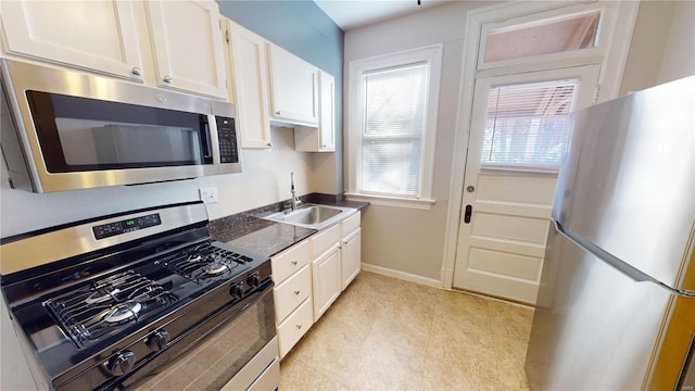 kitchen featuring white cabinets, appliances with stainless steel finishes, a wealth of natural light, and sink