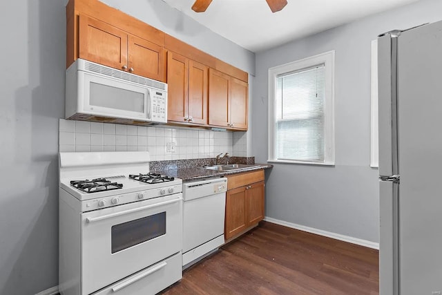 kitchen with backsplash, white appliances, ceiling fan, sink, and dark hardwood / wood-style floors