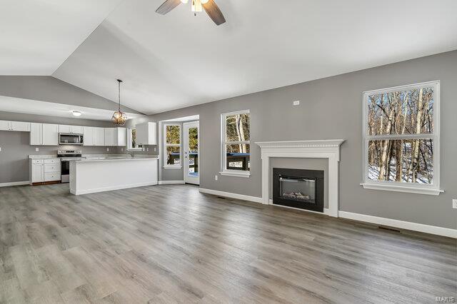 unfurnished living room featuring ceiling fan, hardwood / wood-style flooring, and lofted ceiling