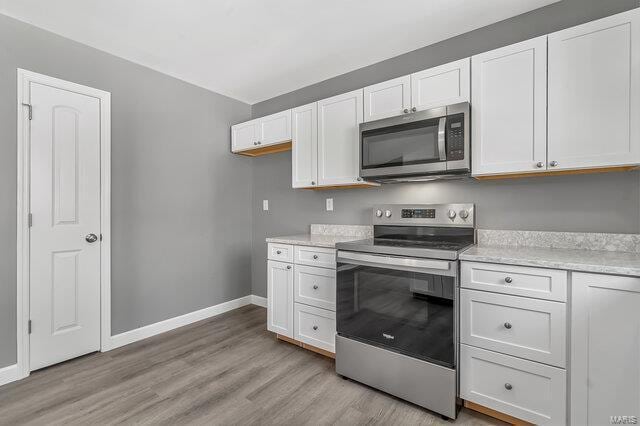 kitchen featuring light wood-type flooring, stainless steel appliances, and white cabinetry