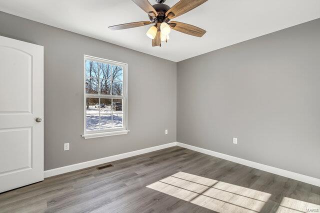 empty room with ceiling fan and dark hardwood / wood-style floors