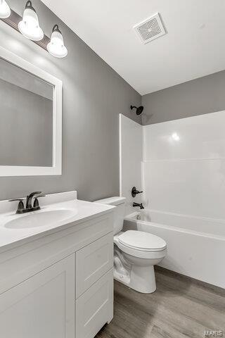 full bathroom featuring toilet, wood-type flooring, vanity, and bathtub / shower combination