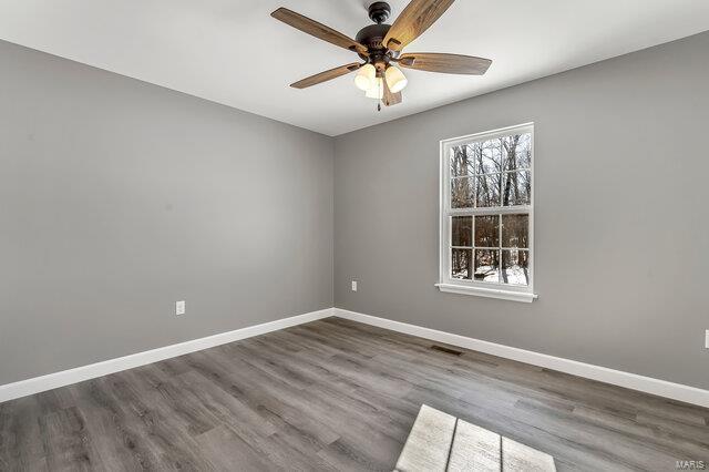 empty room with ceiling fan and dark hardwood / wood-style flooring