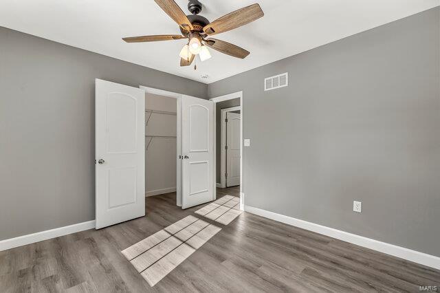 unfurnished bedroom featuring ceiling fan, light hardwood / wood-style floors, and a closet