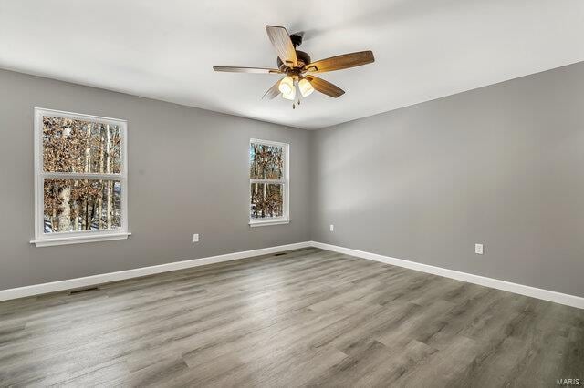 spare room with ceiling fan, a wealth of natural light, and hardwood / wood-style flooring