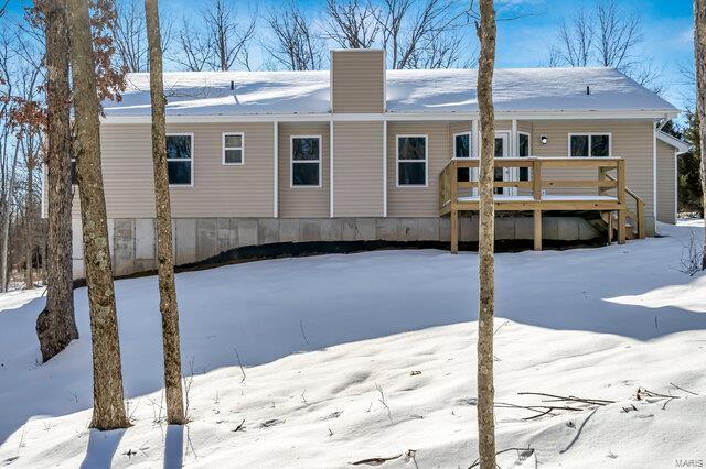 snow covered rear of property with a deck