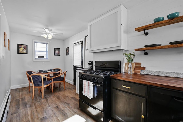 kitchen featuring ceiling fan, white cabinetry, baseboard heating, black range with gas stovetop, and butcher block countertops