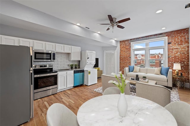 interior space featuring ceiling fan, light hardwood / wood-style floors, sink, and brick wall