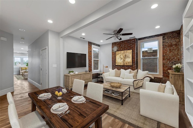 dining space featuring ceiling fan, brick wall, and light hardwood / wood-style flooring