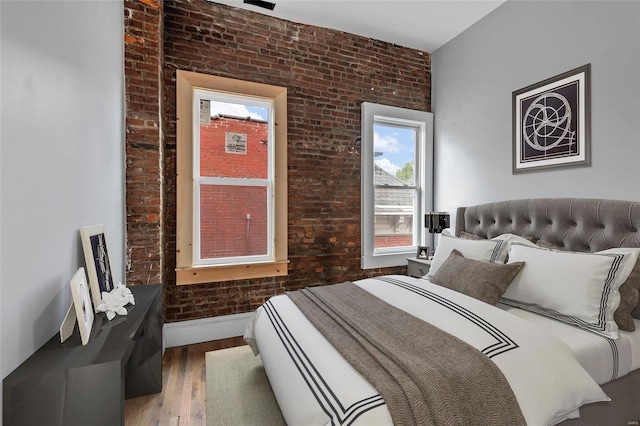 bedroom featuring hardwood / wood-style flooring and brick wall