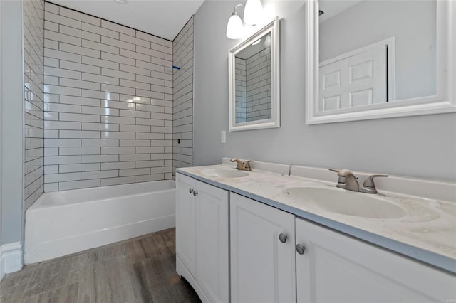 bathroom with hardwood / wood-style flooring, vanity, and tiled shower / bath